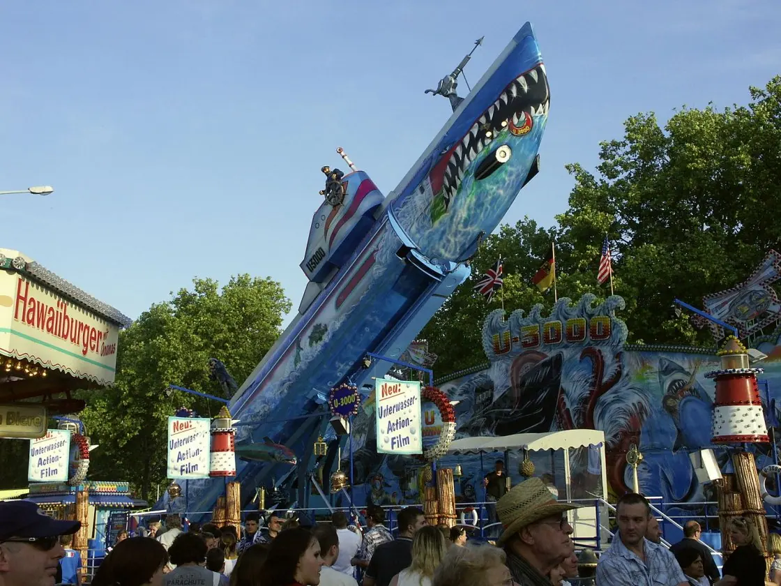 Das Tauchboot U3000 im Abendlicht steil aufgerichtet über dem Kirmesplatz, davor Besucherinnen und Besucher.