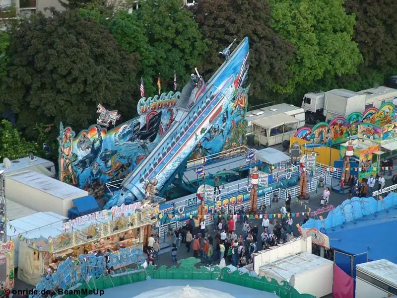 Blick von oben auf den Festplatz: das U3000 zwischen weiteren Fahrgeschäften, umgeben von Besucherströmen.